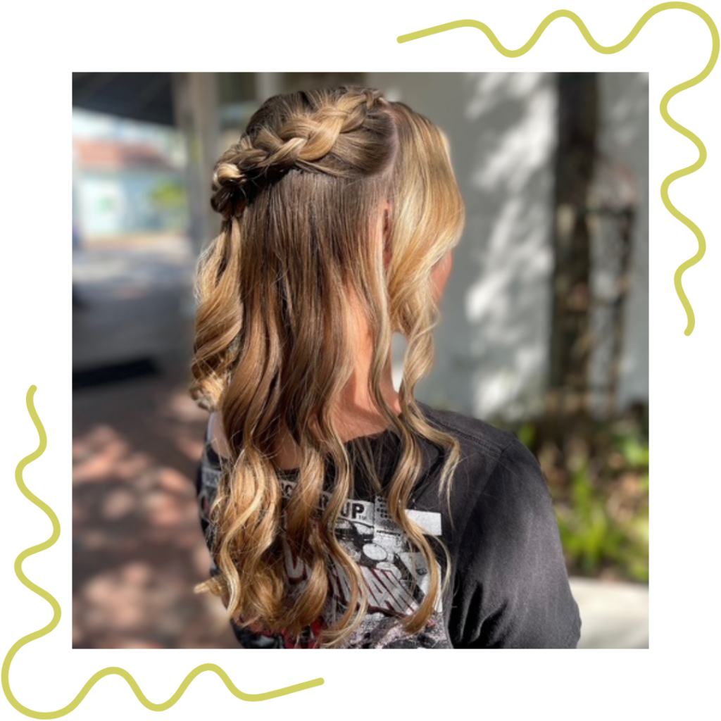 Woman with long, wavy hair featuring a braid at the top, standing outdoors in a black shirt. - Detlev Lifestyle Salon in Coconut Grove, FL