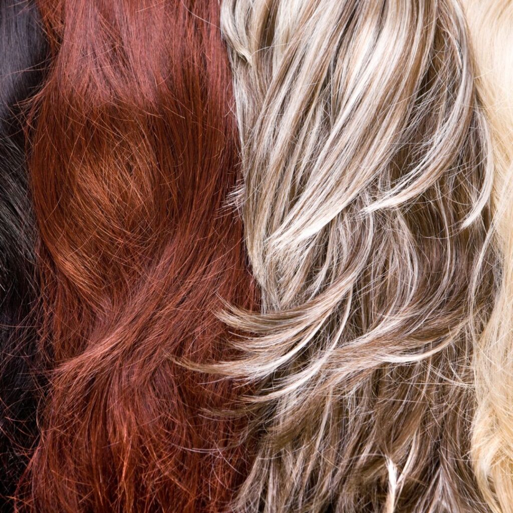 Close-up of various hair strands in black, red, and blonde shades, showcasing texture and natural waves, epitomizing gorgeous hair. - Detlev Lifestyle Salon in Coconut Grove, FL